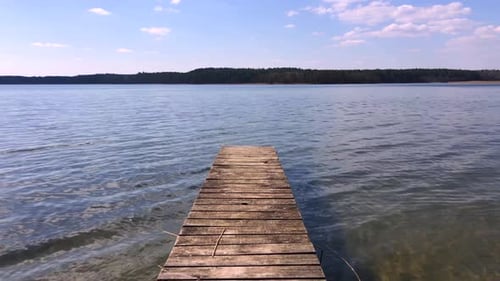 Wooden pier beside a picturesque lake.Soft wave on. the surface of the water in the lake.