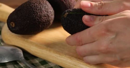 Cutting fresh avocado on wooden cutting board