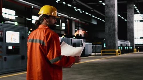 Engineer Inspecting Technical Plans and Sketches in Heavy Industry Workshop