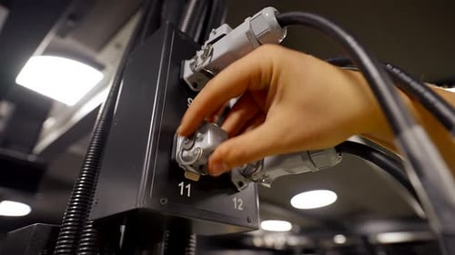 Worker Inserts Wire, Square Plug into Power Outlet