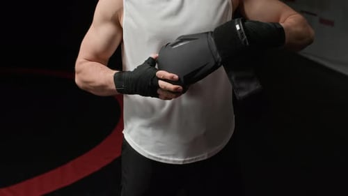 Fighter Putting on Black Boxing Gloves