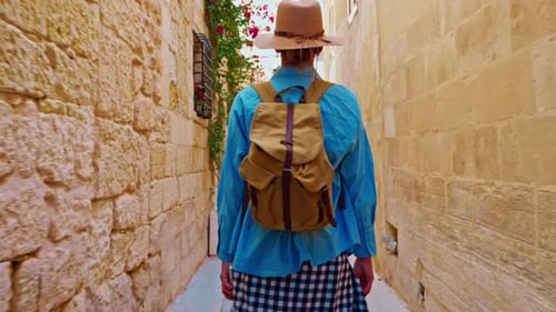 Woman with Backpack Walks Down Quaint European Alleyway