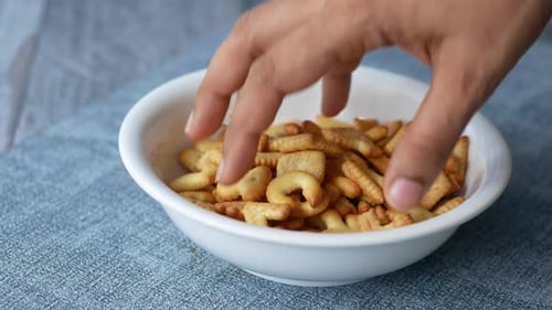 Hand Selecting Alphabet Crackers from White Bowl