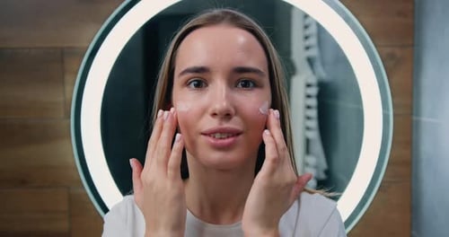 Close Up Portrait of Pretty Woman Using Moisturizing Face Cream and Smiling Looking at Camera