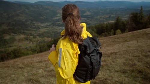 Woman Hiking in Mountains Wearing Bright Yellow Raincoat
