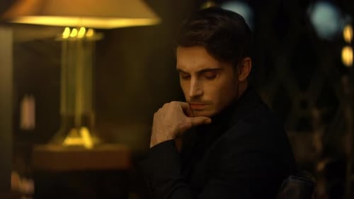Pensive Man Sits Under Lamp at Night