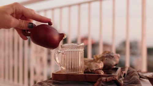 Pouring Tea from Teapot into Mug