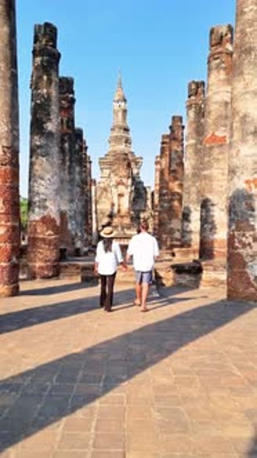 Un homme et une femme se promènent dans un temple historique (Wat Mahathat, Sukhothaï, Thaïlande)