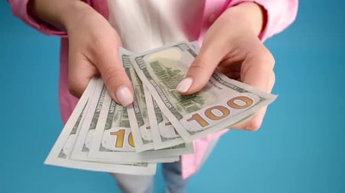 Close-up off female hands counting a stack of hundred-dollar US banknotes. A businesswoman is counti