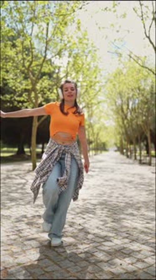 Young Woman Dancing and Listening to Music in Park