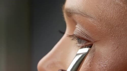 Professional Makeup Artist Applying Shimmering Eyeshadow on Model's Eyelid Utilizing Specialized