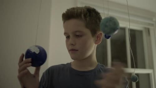 Teenager boy playing with globes in bedroom