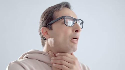 Man Massages Aching Throat Indoors in Close Up