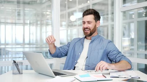 Successful Man Celebrating at Computer in Modern Office