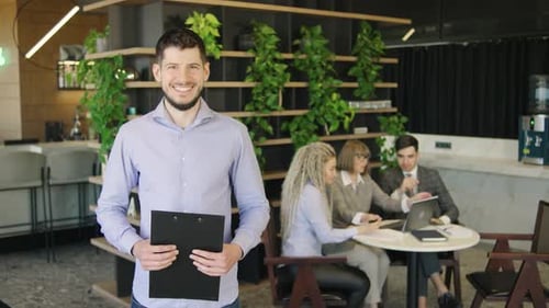 Man Smiles Holding Clipboard in Modern Office