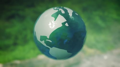 Three-dimensional earth globe made of glass rotates in front of green natural eco background