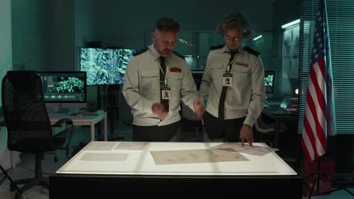 Two Adults Reviewing Maps in a Dark Room