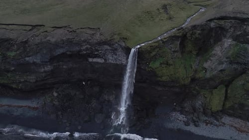 Aerial View Of Waterfall Cascading From Cliff Into Ocean In Iceland
