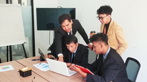 Diverse business team collaborating analyzing data on laptop strategizing future growth