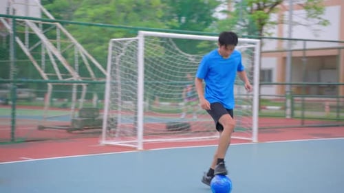 Asian young sportsman practicing football playing in the outdoors stadium.