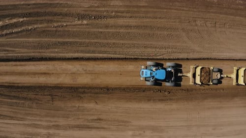 Luftaufnahme eines Traktors von oben nach unten, der große Bodenmengen bewegt.