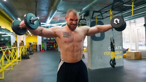 Muscular Man Working Out With Dumbbells in Gym