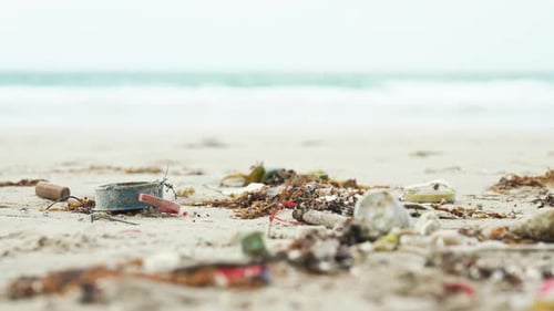 Slow Moving Shot of Plastic Waste and Trash Scattered on a Polluted Beach, Highlighting Environmenta