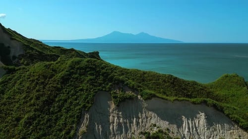 Rocks of an uninhabited island in the Mediterranean Sea. Clip. Forested green hills and blue sea