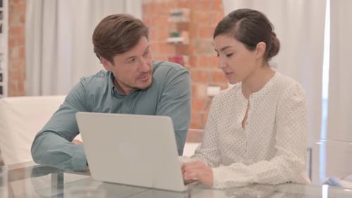 Adults Collaborating on a Laptop at Home