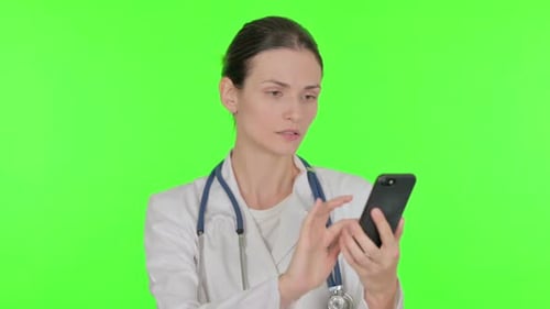 Female Doctor Browsing Smartphone on Green Background
