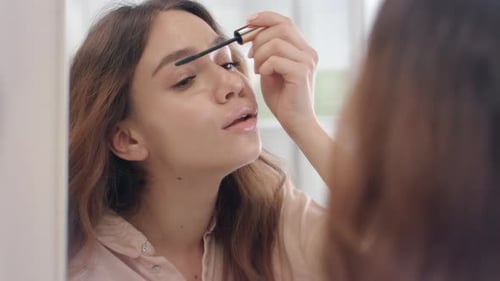 Schöne Frau, die Wimperntusche für die Wimpern verwendet, Vorderspiegel im Badezimmer. Portrait Frau bewirbt sich