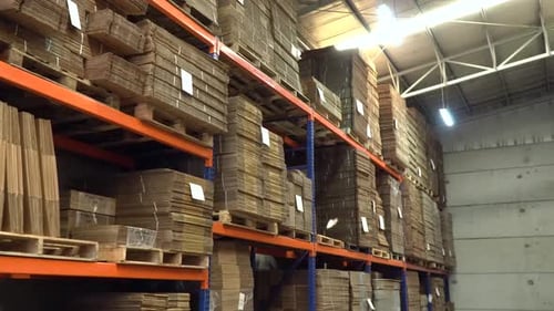 Marcher dans la zone de stockage d'un entrepôt remplie de boîtes en carton sur les étagères (un centre de distribution)
