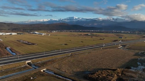 Vue par drone d'une route rurale près des montagnes lors d'un coucher de soleil doré en hiver