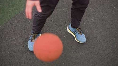 Man Dribbling Basketball on Outdoor Court