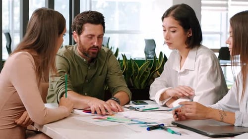 Group of Colleagues Works with Statistical Documents at Table
