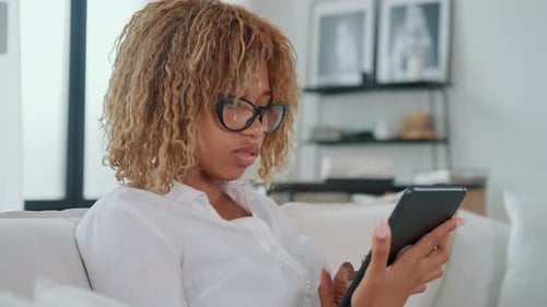 Woman Relaxes on Sofa While Using Tablet Device