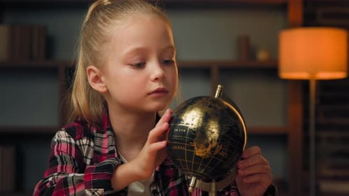 Girl Examining Globe in a Warmly Lit Room