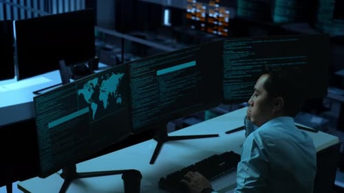 Side View Of Bored Asian Man Write Code With Multiple Computer Screens In office