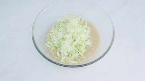 Preparing zucchini fritters, shredded zucchini in a bowl