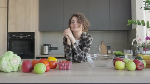 Smiling Woman with Fresh Produce in Kitchen