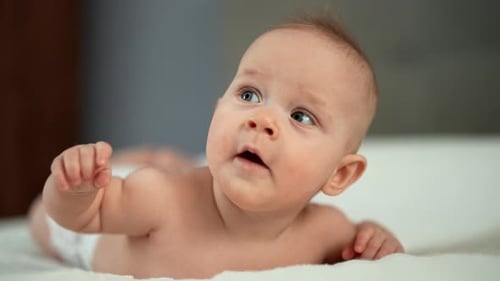 Cute Baby Lying on Stomach on White Blanket