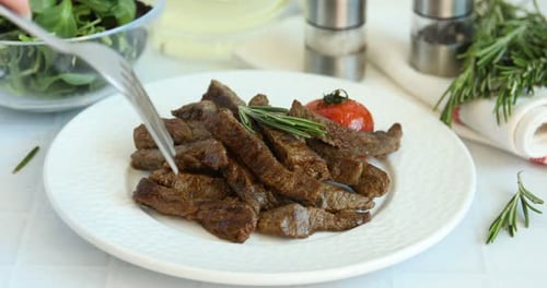 Frau isst leckeres Rindfleisch am weißen Tisch, Nahaufnahme