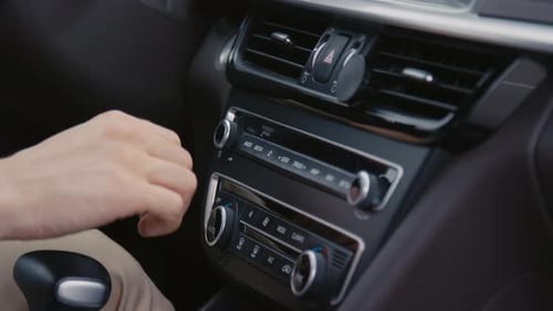 Hand Adjusting Controls on Car Dashboard