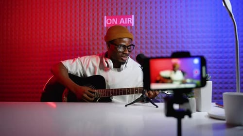 Adult Plays Guitar in Home Recording Studio