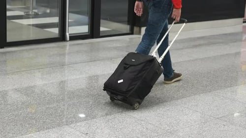 Pessoa caminha no aeroporto com mala, bagagem de mão de passageiro, bagagem rolante de viajante
