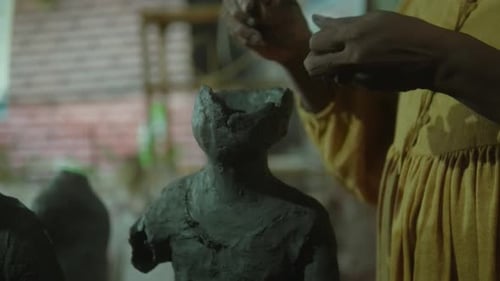 Close-up of hands sculpting a clay figure, highlighting the art of craftsmanship and creativity