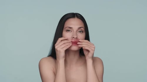 Brunette Woman Doing Facial Skin Care Procedures A Woman Applies Red Hydrogel Patches to Her Lips on