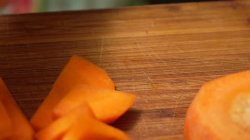 Person cutting fresh carrots on cutting board.