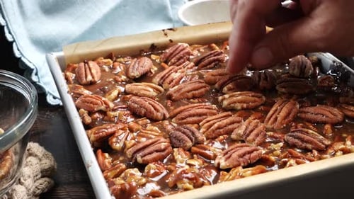 Baking delicious caramel pecan brownies. Using my hands to place whole pecans into the caramel toppi