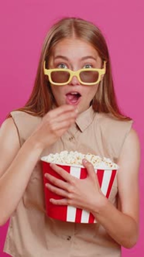 Woman with Popcorn and 3D Glasses Against Pink Backdrop
